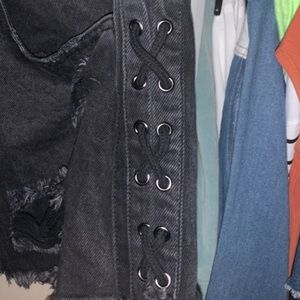 Black denim shorts with rips and ties on the side.